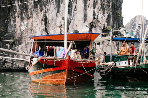 Colour Boats with Masts against Gray Cliff with People and a Dog