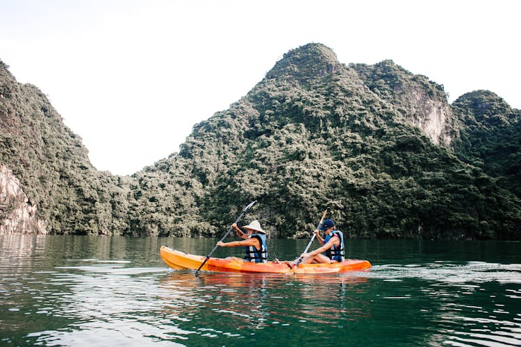 People Rowing In Kayak In Mountain Landscape