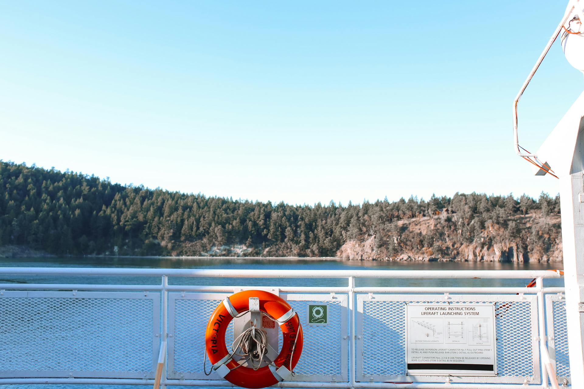 Serene ferry ride with a lifebuoy against a forested landscape.