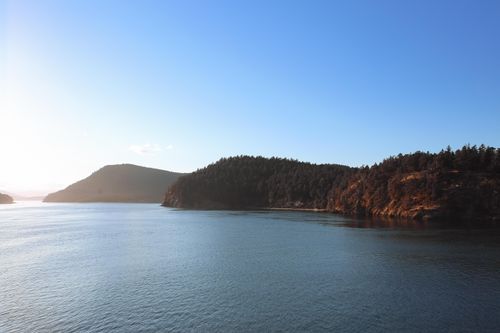 Free Serene view of a tranquil island with forested hills surrounded by calm waters under a clear sky. Stock Photo