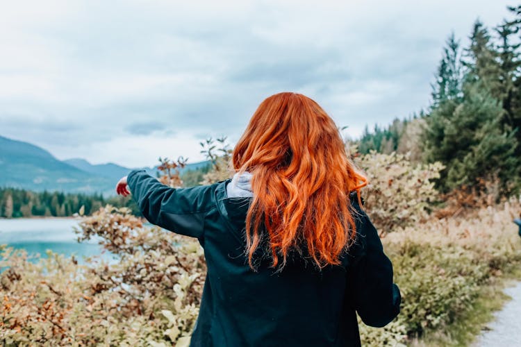 Back View Of A Person Pointing Towards A Body Of Water