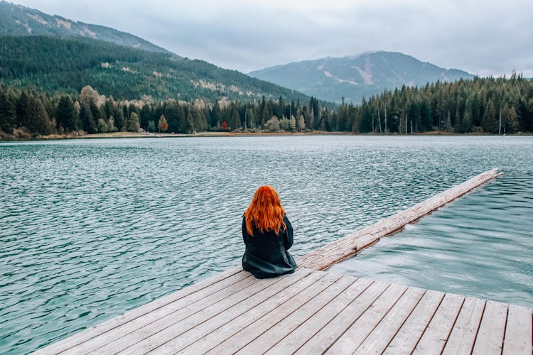 Back View Of A Person Sitting On A Dock