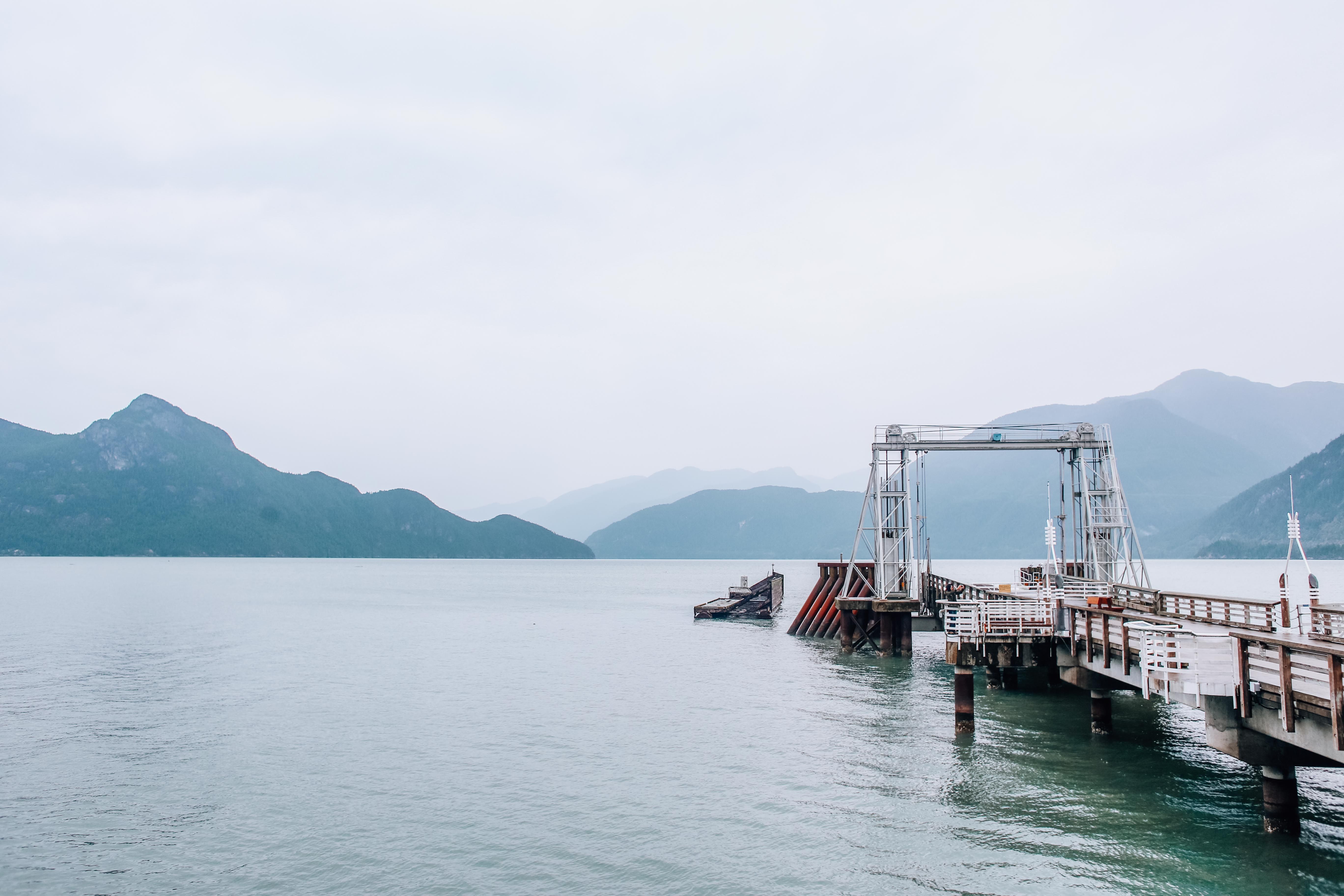 Serene misty view of Porteau Cove's ferry dock with mountains in British Columbia, Canada.