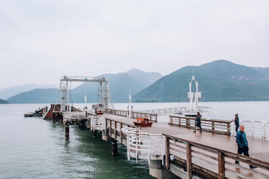People walking on a boardwalk with a stunning lake and mountain backdrop. Peaceful and serene setting.