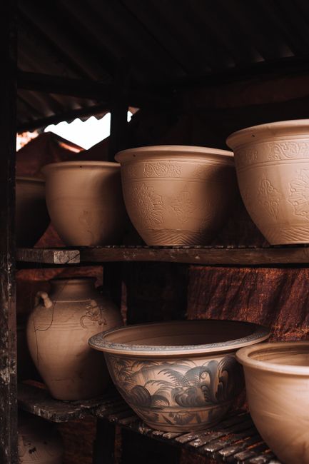 Artisan ceramic pots in earthy tones nestled on wooden shelves. Perfect for decor inspiration.