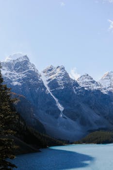 Majestic snow-covered mountains reflected in Moraine Lake's blue waters.