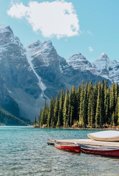 Idyllic view of canoes on a tranquil lake surrounded by snowcapped mountains.