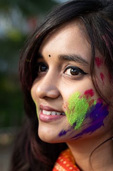 Close-up portrait of a joyful woman covered in vibrant Holi colors, celebrating the festival in Patna, India.