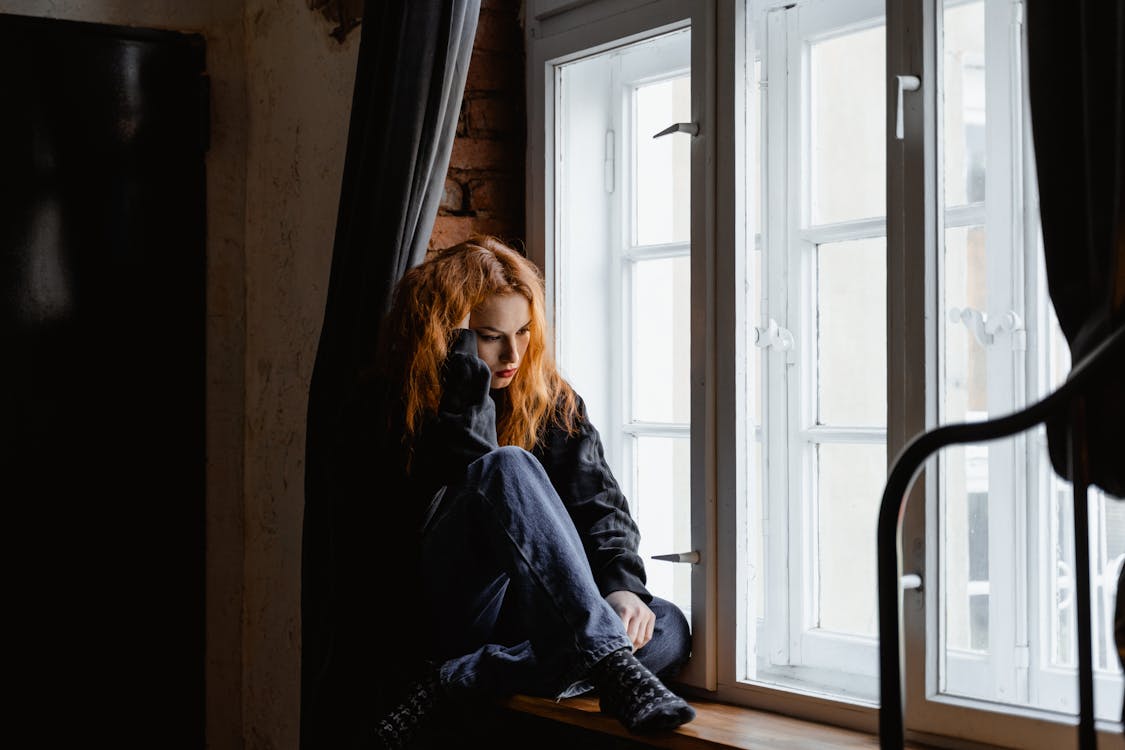 Free Woman in Black Leather Jacket Sitting on Brown Wooden Floor Stock Photo