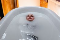 Person Lying in Bathtub with White Water