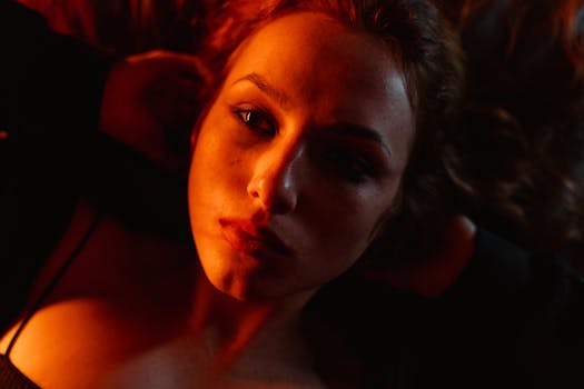A captivating close-up portrait of a young woman under red lighting.