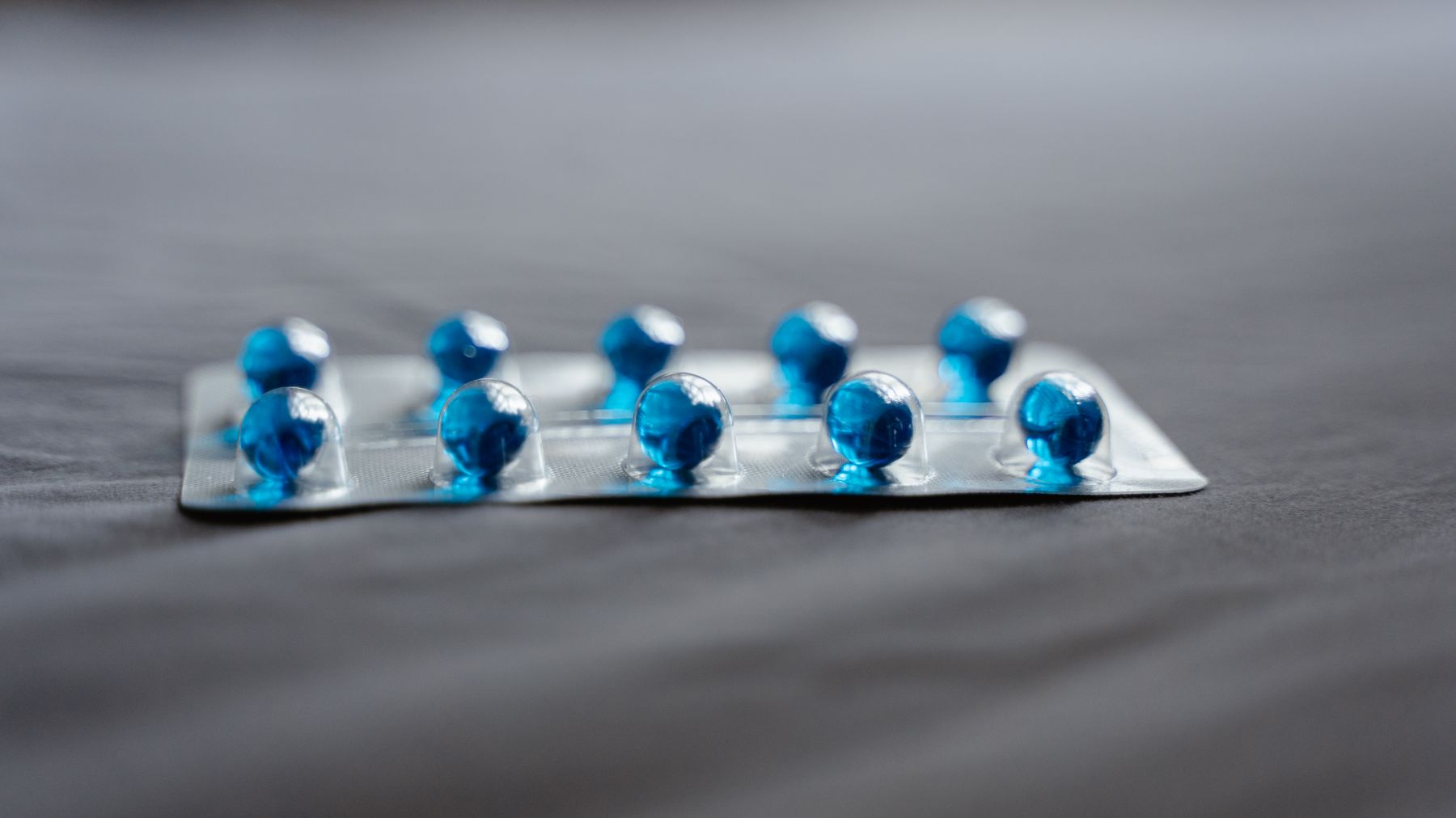 Detailed image of blue pills in a blister pack on a soft surface.