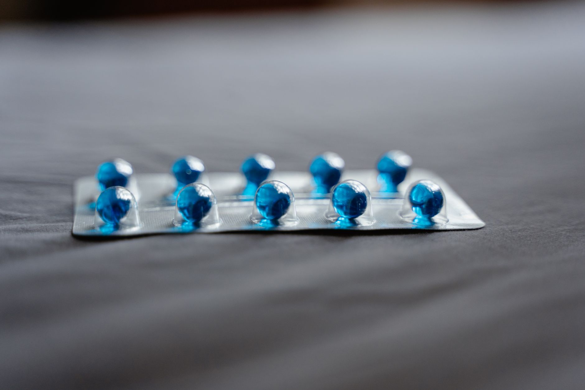 Detailed image of blue pills in a blister pack on a soft surface.