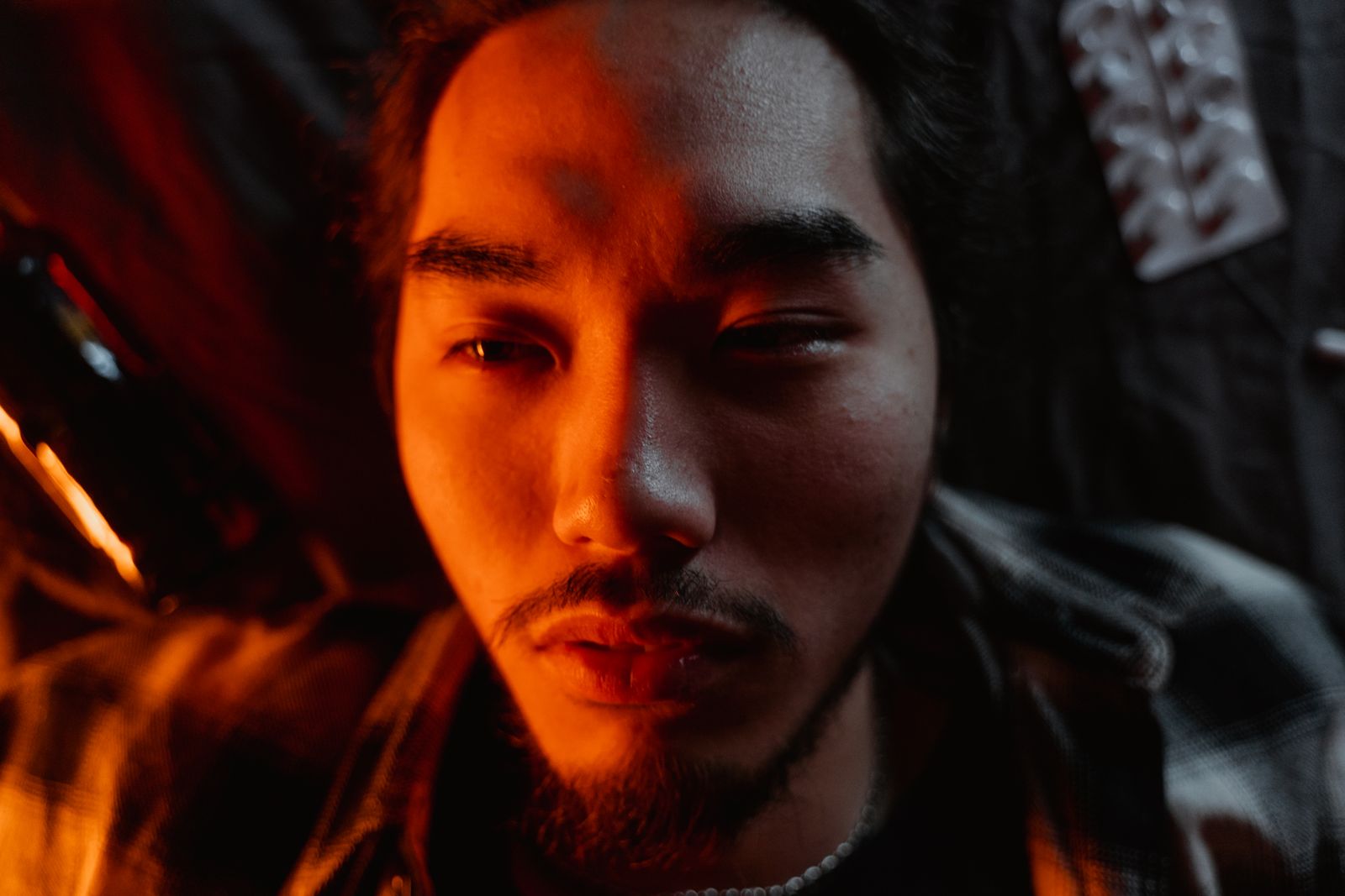Close-up of a young man under moody warm lighting. Photo by MART PRODUCTION on Pexels