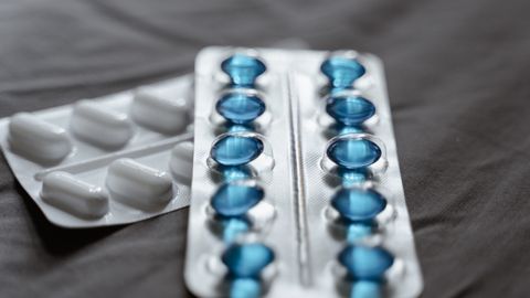 Detailed view of medication in blister packs showcasing blue softgel capsules and white pills.