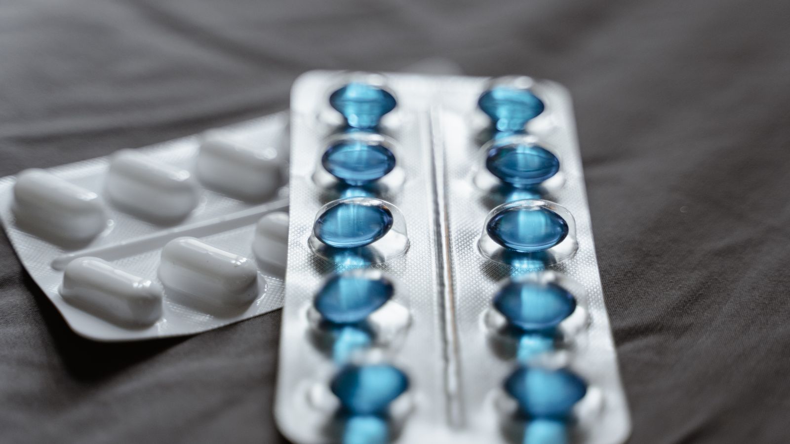 Detailed view of medication in blister packs showcasing blue softgel capsules and white pills.