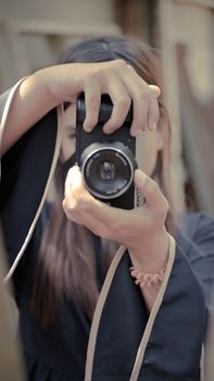 Young woman focusing camera lens, capturing an image in soft light setting.
