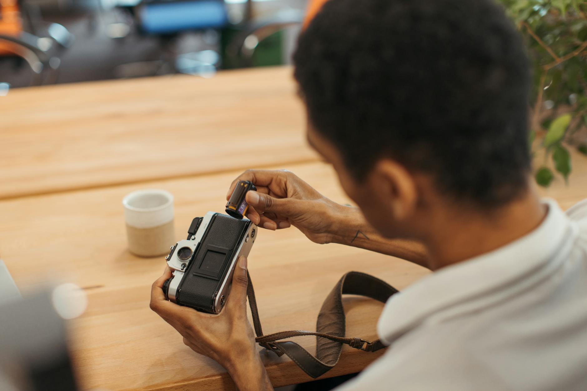 Person loading a roll of film into a vintage camera, focused with hands visible.