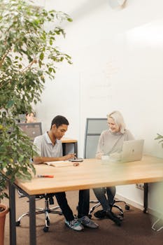 Two diverse colleagues working on a project in a bright, creative office setting.