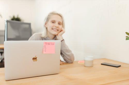 A Smiling Woman in Beige Long Sleeve Shirt Sitting In Front of a Laptop

