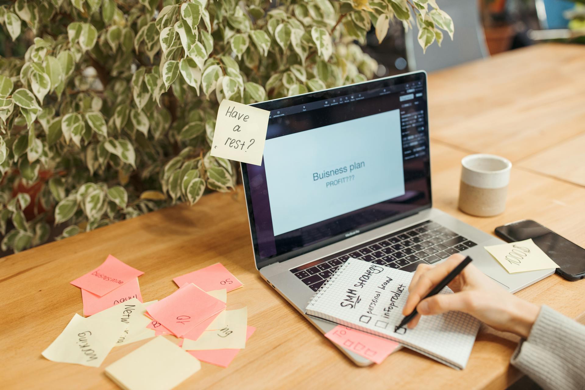 A workspace with a laptop, sticky notes, and a notepad for business planning.