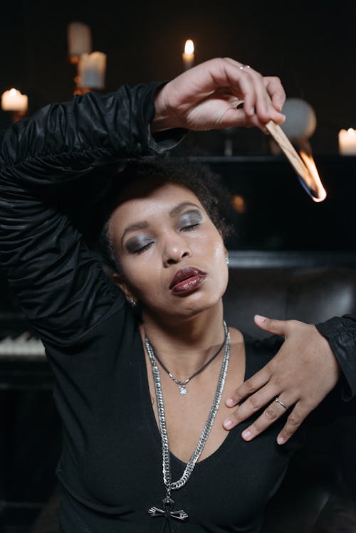 Woman in Black Long Sleeve Shirt Holding a Burning Match Stick