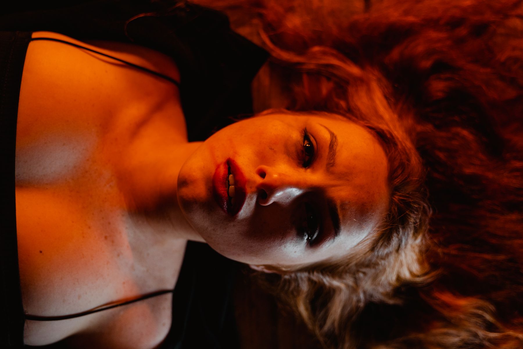 Close-up portrait lit in deep red, lying down — photo by MART PRODUCTION on Pexels