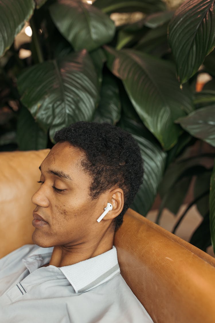 A Man Lying On The Chair Using Earphone