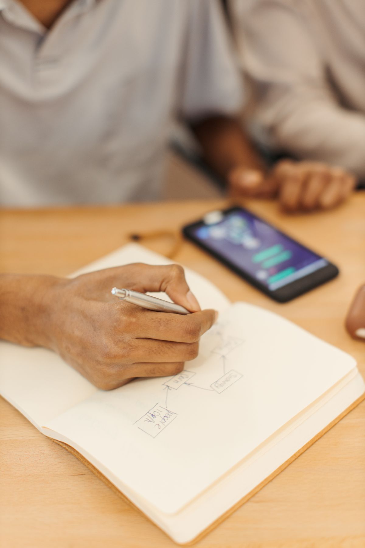 Sketching a payment flow in a notebook next to a phone
