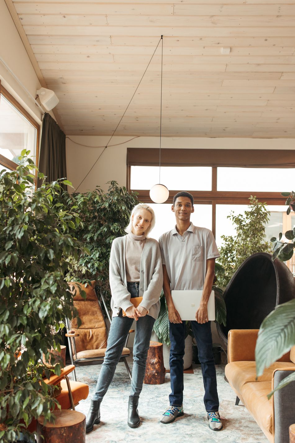 Two colleagues talking beside plants in a bright studio office. Photo by Anastasia Shuraeva on Pexels.