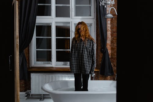 Free A Woman Standing on a Filled Bath Tub with Clothes On Stock Photo