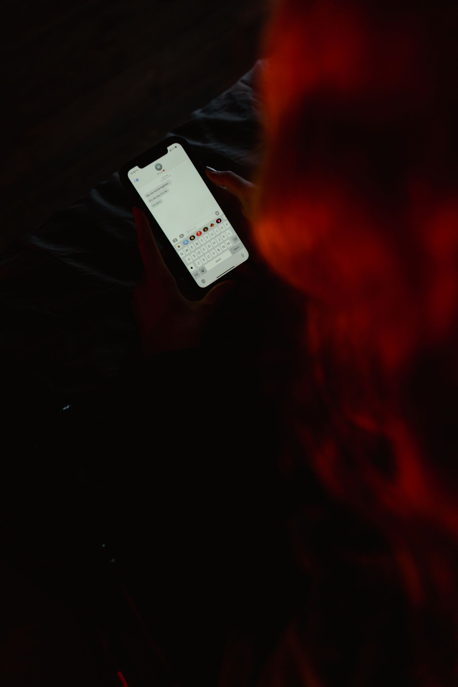 Primer plano de una persona escribiendo en un smartphone en un entorno oscuro