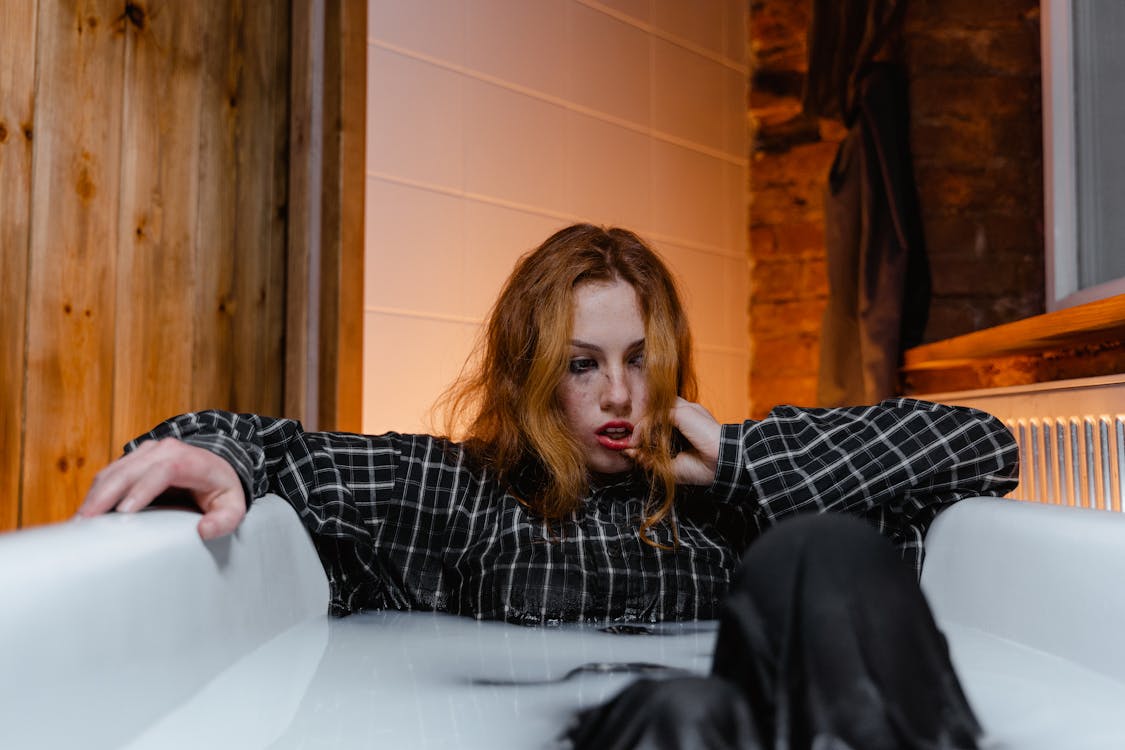 depressed woman sitting in a bathtub stock 