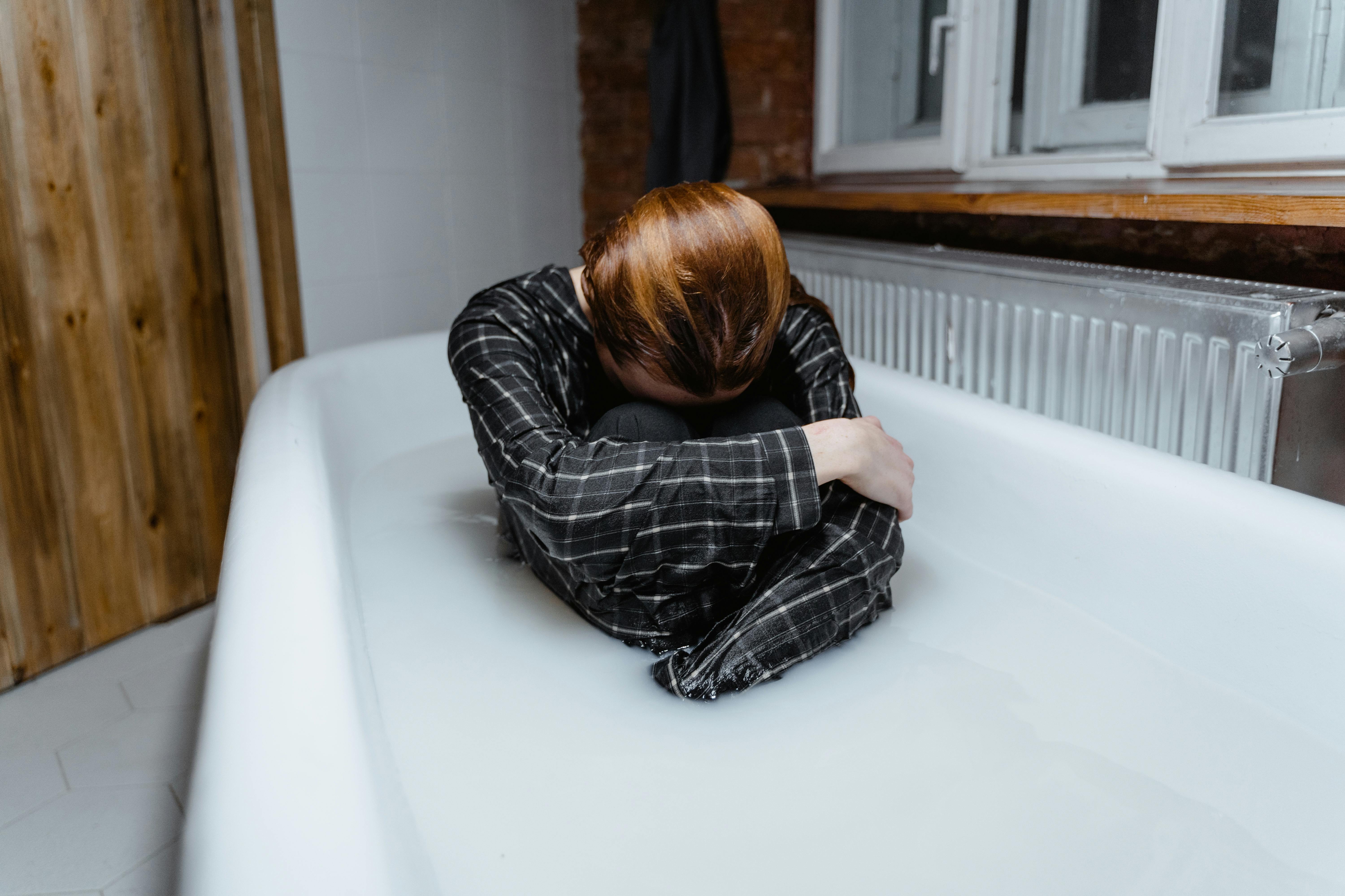 woman in black and white plaid dress shirt lying on white bed