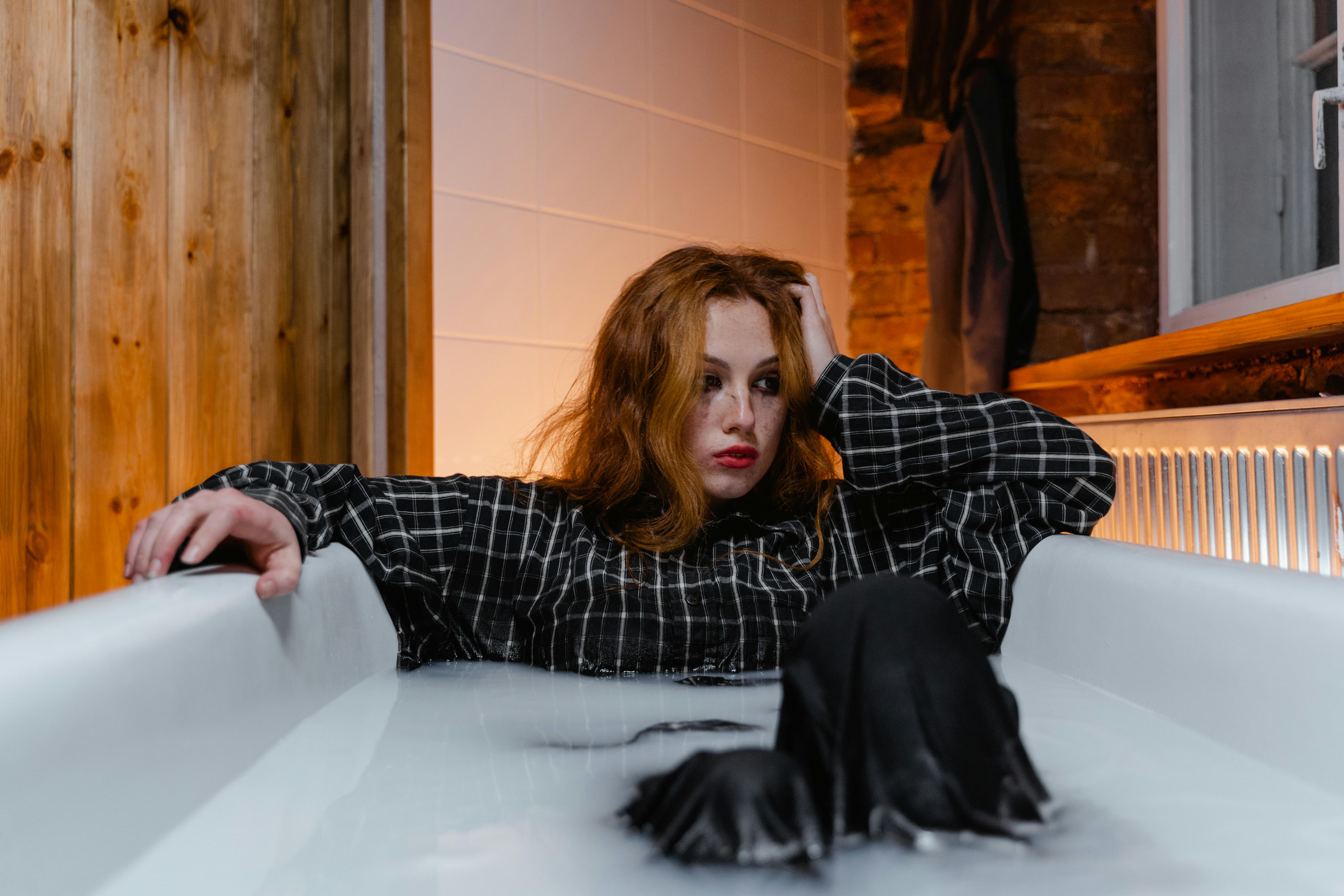 depressed woman sitting in a bathtub