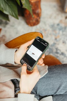 Close-up of hands holding a smartphone indoors, focusing on the screen.