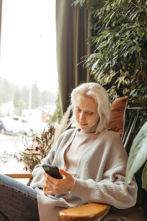 A Woman Sitting on a Chair while Using a Cellphone