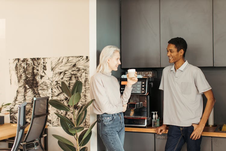 Interracial Co-workers Having Fun Conversation In Office Pantry