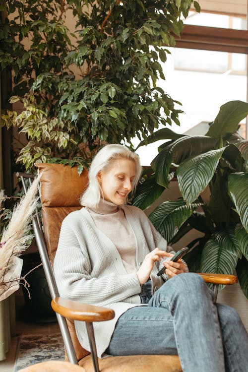 Woman Sitting on a Chair while Using Mobile Phone