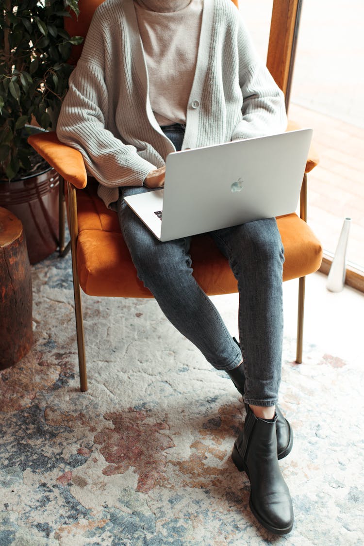 Person Sitting On A Chair While Using Laptop