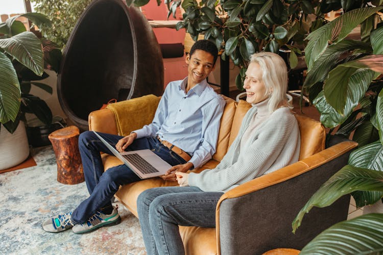 Man And Woman Laughing While Sitting On A Sofa 