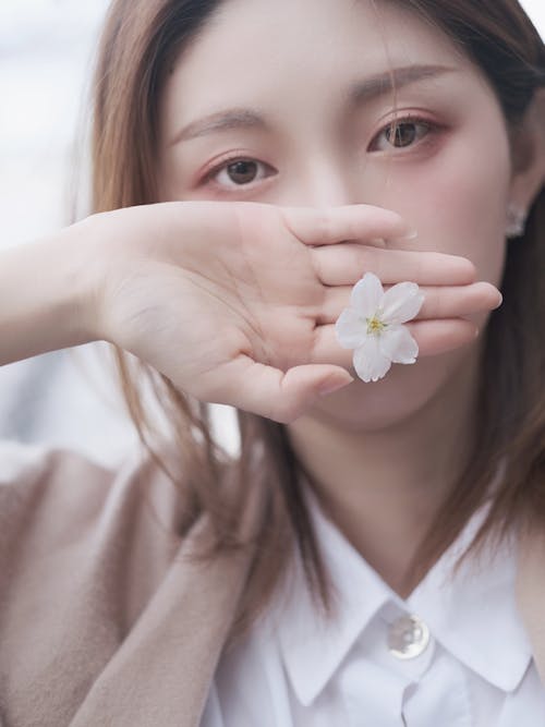 Close-Up Shot of a Woman Holding a White Flower