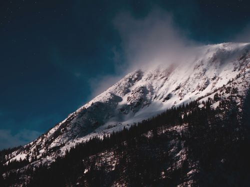 Free A dramatic snow-covered mountain under a star-filled sky at night, showcasing winter's beauty. Stock Photo