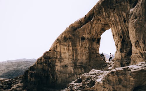 Free People Standing Under Natural Arch in Eilat Mountains Stock Photo