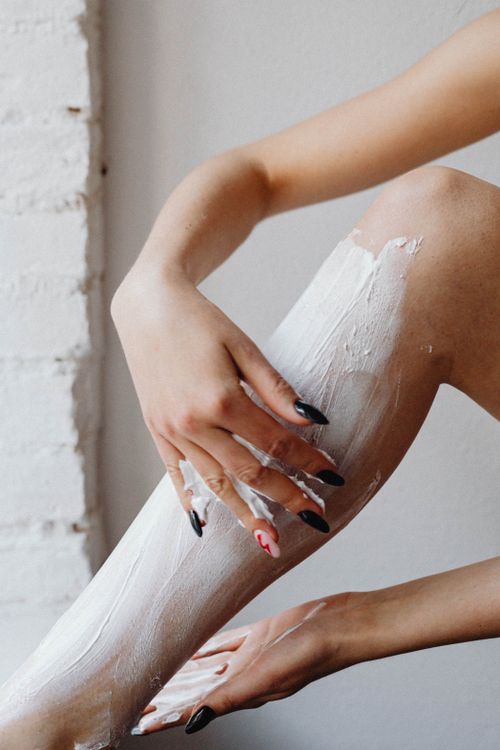 Free Close-up shot of a woman applying shaving cream on her leg for skincare. Stock Photo