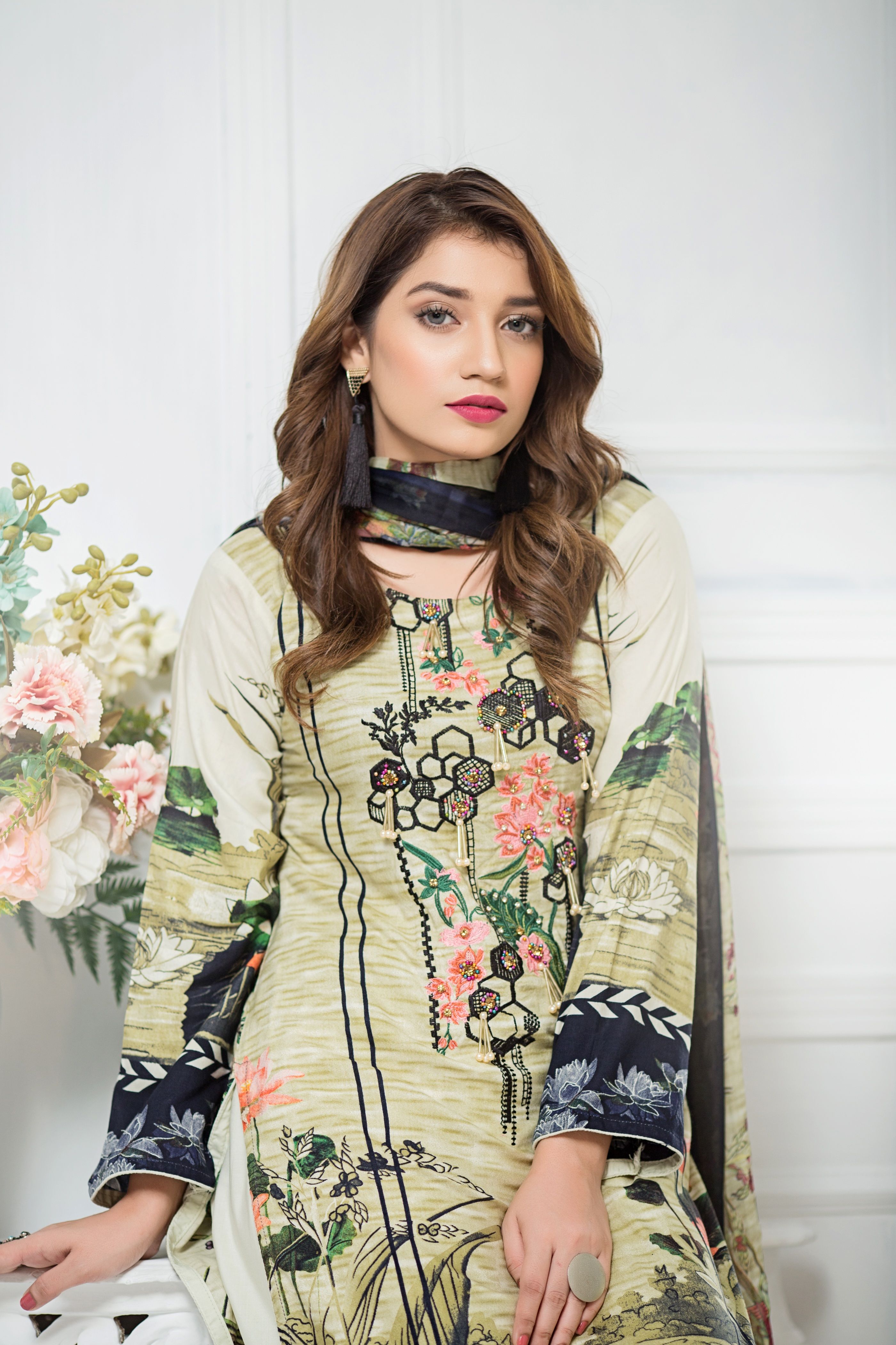 Stylish portrait of a young woman wearing an elegant embroidered dress, showcasing modern fashion with floral details.
