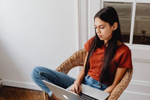 Free Young woman using a laptop in a cozy, minimalist home environment, focused on remote work. Stock Photo