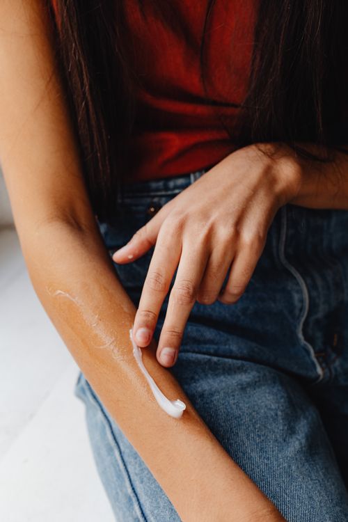 Free Person applying cream on their arm for skincare routine and hydration. Stock Photo