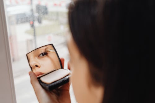 A Woman Using a Mirror to Apply Makeup