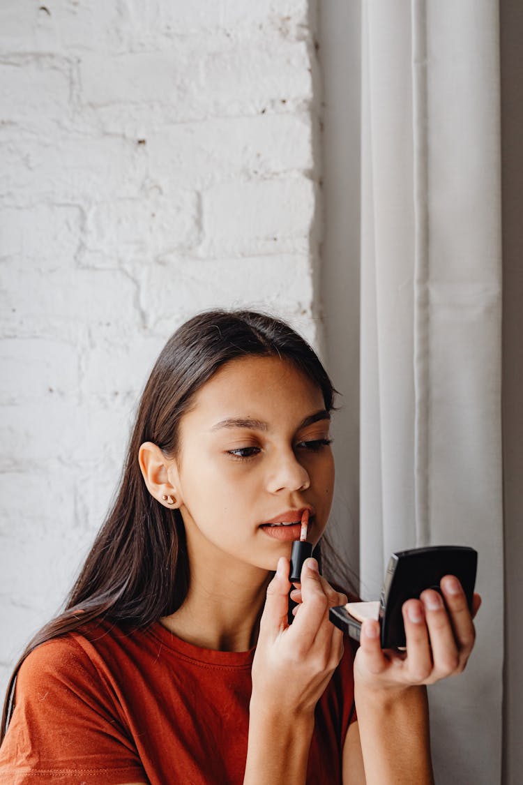 A Woman In Red Shirt Putting Lipstick